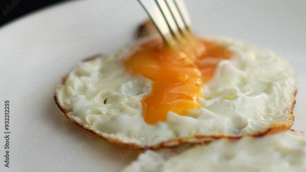 Stir the yolk with a fork.
Chicken egg close-up on a plate Stir the yolk with a fork.
Chicken egg close-up on a plate