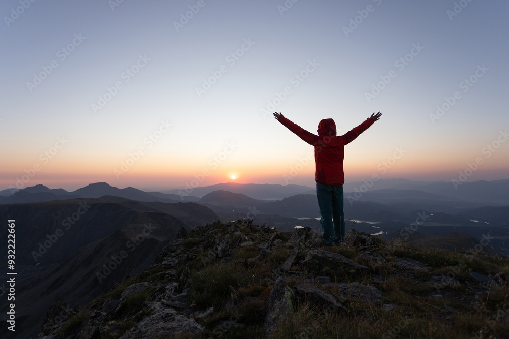 A person in a red jacket is standing on a mountain top A person in a red jacket is standing on a mountain top