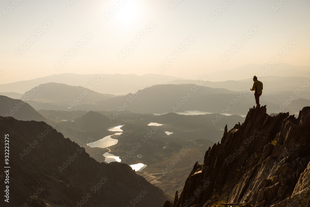 A person is standing on a mountain top, looking out over a beautiful landscape A person is standing on a mountain top, looking out over a beautiful landscape