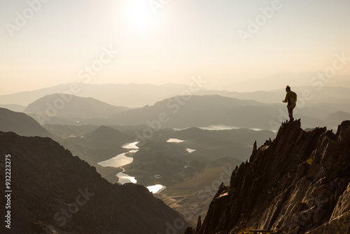 A person is standing on a mountain top, looking out over a beautiful landscape