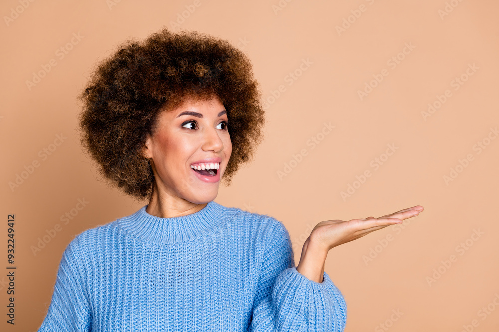 Photo of impressed girl with chevelure dressed blue knit sweater look at product on palm empty space isolated on pastel color background Photo of impressed girl with chevelure dressed blue knit sweater look at product on palm empty space isolated on pastel color background