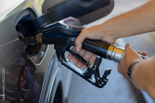 a man is putting gas in his car, his hand near the car,