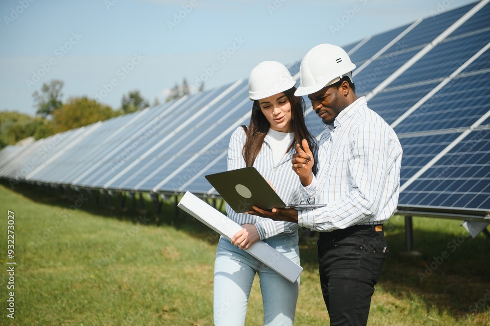 Group of multi ethnic people and safety helmets staring at solar farm.