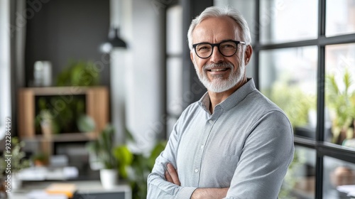 A friendly elderly man smiles in a modern office setting in the middle of the day