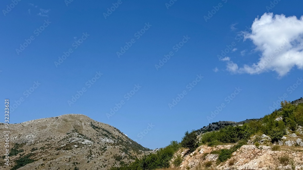A minimalist landscape featuring a rocky hill with sparse vegetation under a bright, clear blue sky. A minimalist landscape featuring a rocky hill with sparse vegetation under a bright, clear blue sky.