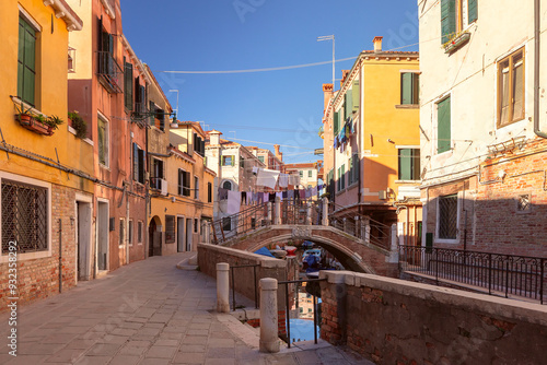 Photos A Venetian canal lined with brick buildings, a small boat, and laundry hanging a