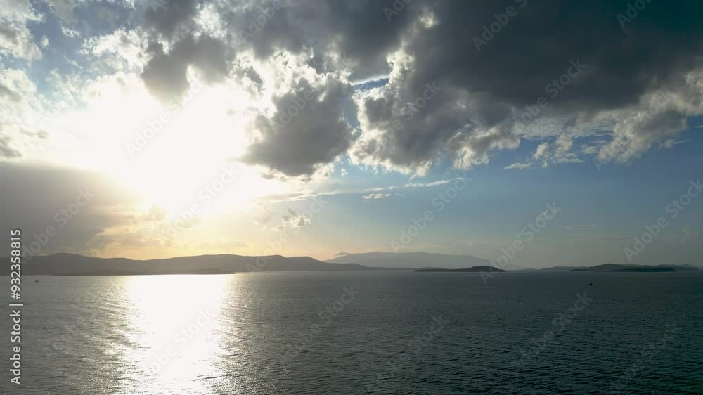 The sun is peeking through fluffy clouds above the ocean, casting a beautiful afterglow on the water and creating a stunning natural landscape The sun is peeking through fluffy clouds above the ocean, casting a beautiful afterglow on the water and creating a stunning natural landscape