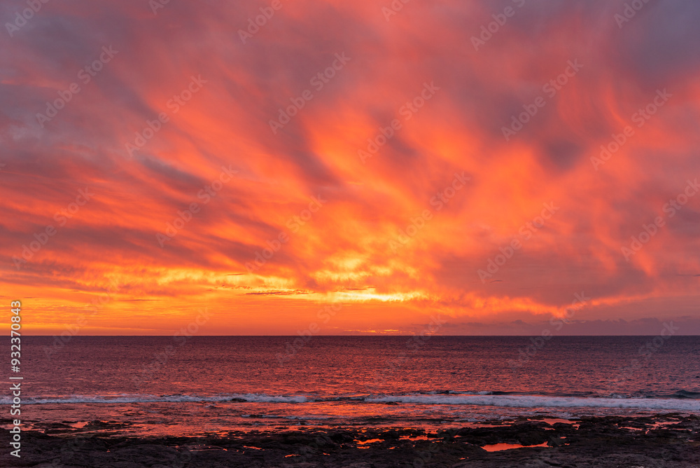 Obraz premium Cloudy pInk orange sunset over ocean and reef with color reflections in water