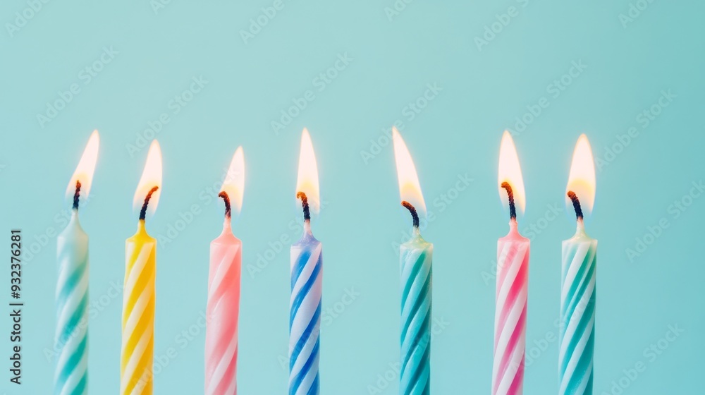 Row of lit birthday candles on teal Row of lit birthday candles on teal