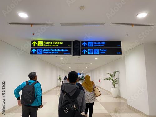 Passengers walking through an airport corridor with directional signage photo