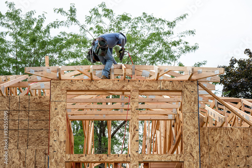 Fényképezés New residential home construction in framing stage, workman on the roof rafters
