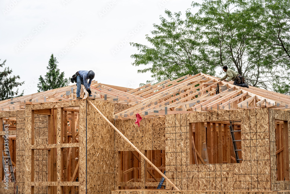 New residential home construction in framing stage, two workers on the ...