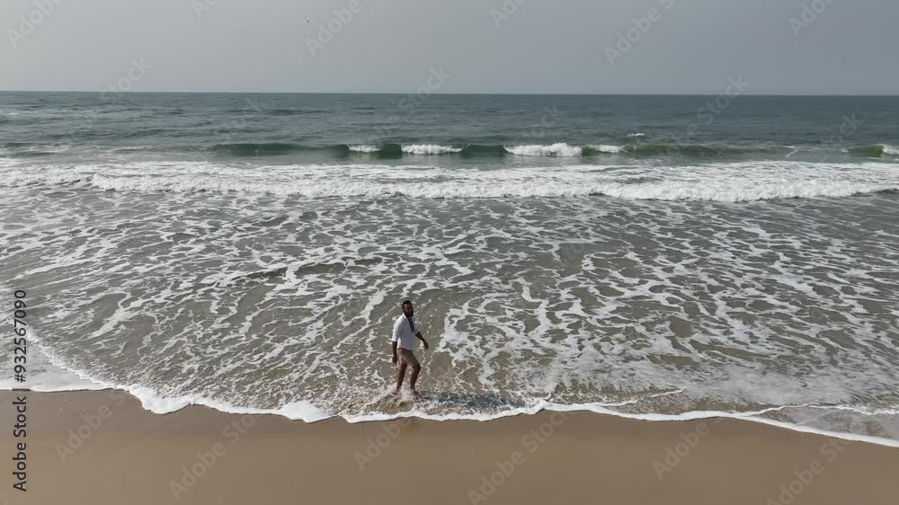 Running and walking on the beach during a sunny morning. Aerial view with camera following the person. Running and walking on the beach during a sunny morning. Aerial view with camera following the person.