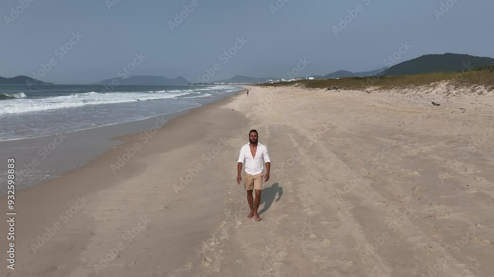 Running and walking on the beach during a sunny morning. Aerial view with camera following the person. Running and walking on the beach during a sunny morning. Aerial view with camera following the person.