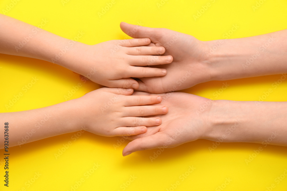 Fototapeta premium Female and children's hands on yellow background, closeup
