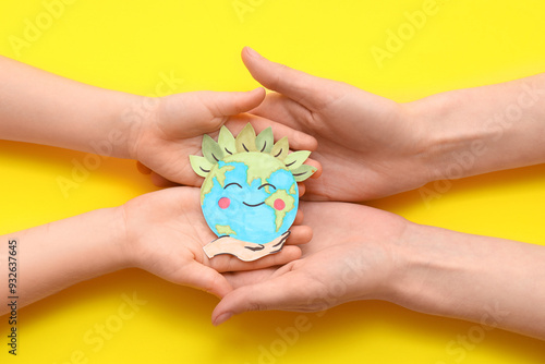 Wallpaper Mural Child's and female hands with paper planet Earth on yellow background, closeup Torontodigital.ca
