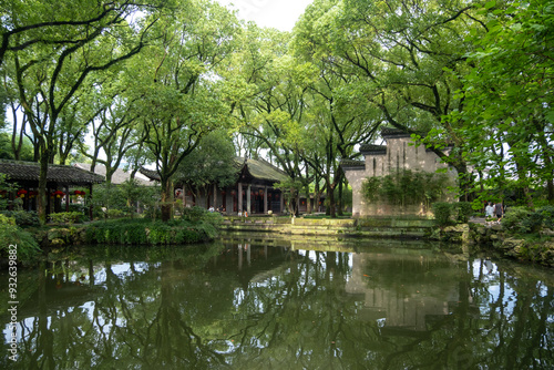 Fotografía A tranquil pond reflects the lush greenery of towering trees and traditional Chinese architecture in Tianyi Ge’s historic garden in Ningbo, China