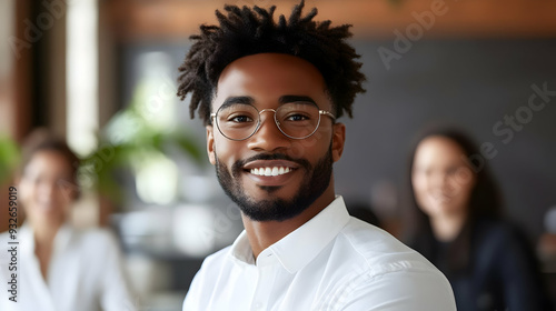 A smiling man in glasses in a modern office setting.