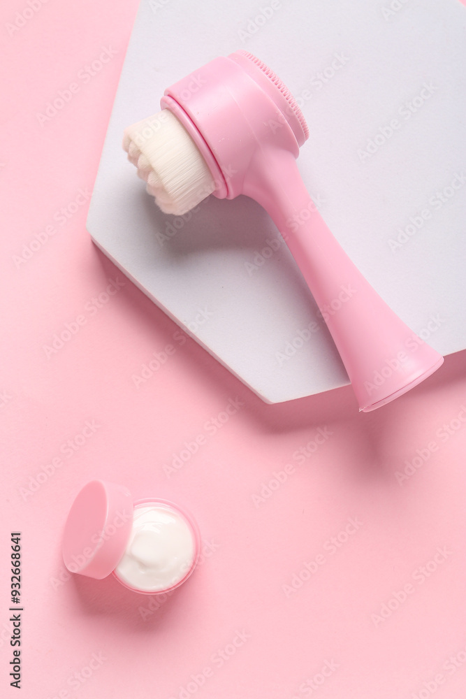 Fototapeta premium Plaster stand, facial massage brush and jar of cosmetic product on pink background, closeup