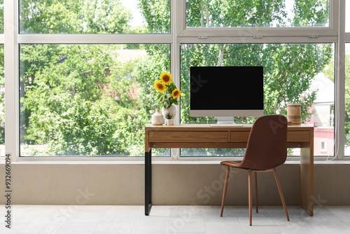Beautiful workplace with computer and sunflowers near window in room