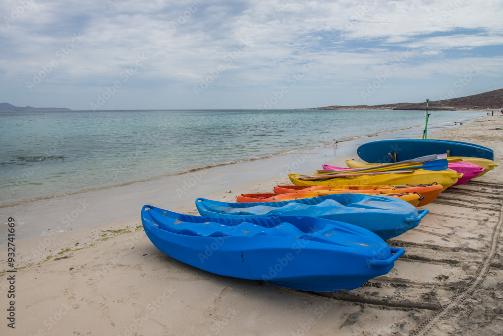 Kayaks on the beach on a cloudy summer vacation morning, facing the sea of Cortes on El Tecolote Beach in La Paz Baja California Sur. Mexico. Seascapes of the baja. Kayaks on the beach on a cloudy summer vacation morning, facing the sea of Cortes on El Tecolote Beach in La Paz Baja California Sur. Mexico. Seascapes of the baja.