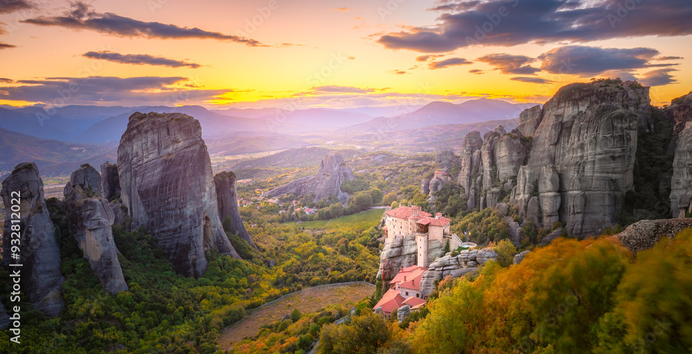 Panoramic landscape of Meteora, Greece at romantic sundown time with real sun and sunset sky. Meteora - incredible sandstone rock formations. The Meteora area is on UNESCO World Heritage.