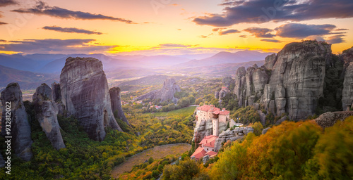 Obraz na płótnie Panoramic landscape of Meteora, Greece at romantic sundown time with real sun and sunset sky. Meteora - incredible sandstone rock formations. The Meteora area is on UNESCO World Heritage. w salonie
