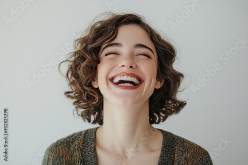 Joyful woman laughing with eyes closed, white background