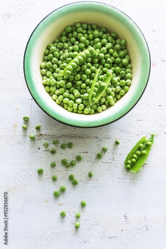 Peeled green peas in a white bowl. Kitchen scene.