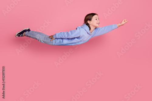 Full size photo of lovely small schoolkid raise fist fly empty space wear hoodie isolated on pink color background