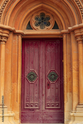 Mdina, Malta. Limestone arches, Corinthian columns, rosette gothic stained glass and a red door photo