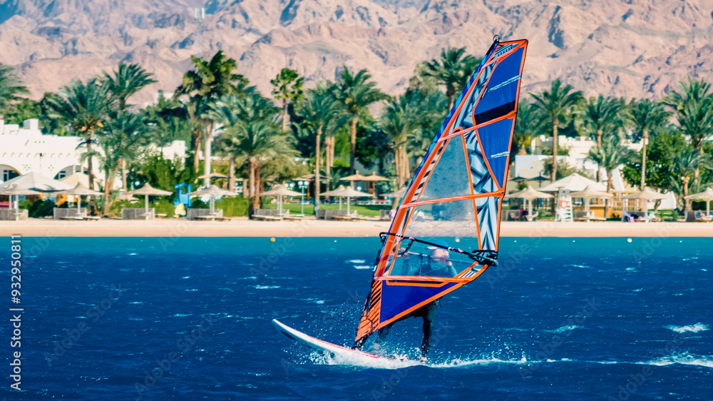 Fototapeta premium surfer rides on the background of the beach with a hotel and palm trees in Egypt Dahab South Sinai