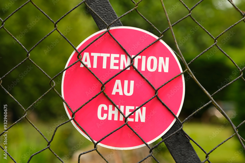 Red sign with french text attention au chien in english beware of the dog on a fence in Cornac Lot Occitanie in Southern France. Red sign with french text attention au chien in english beware of the dog on a fence in Cornac Lot Occitanie in Southern France.