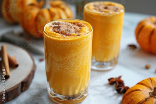 Delicious pumpkin smoothie with whipped cream on top. Garnished with cinnamon and spices on a cozy autumn background with pumpkins and autumn leaves photo