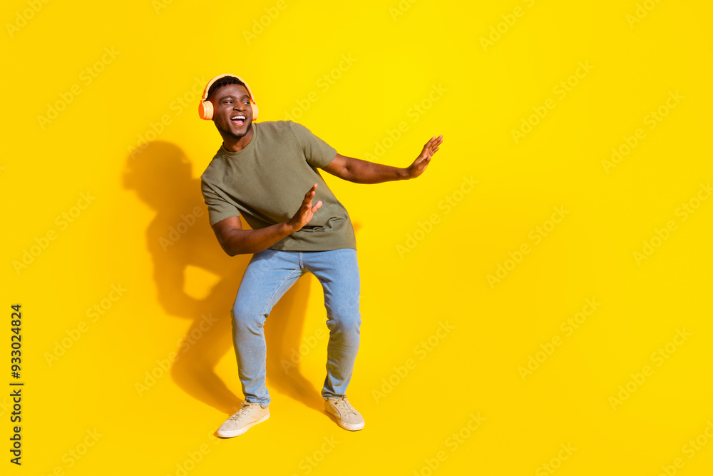 Photo of positive optimistic man wear trendy khaki clothes listen playlist dance empty space isolated on yellow color background Photo of positive optimistic man wear trendy khaki clothes listen playlist dance empty space isolated on yellow color background