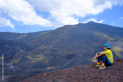 Joven chica con camisa amarilla haciendo senderismo en el Monte Etna: el Parque y el Valle del Bove, Sicilia, Italia.
