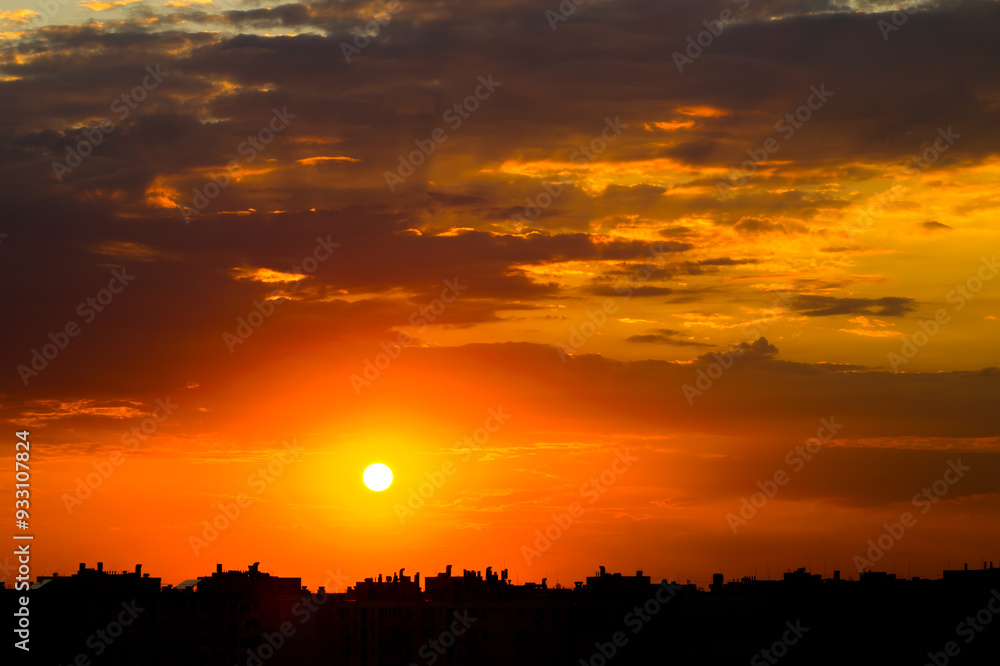 Fototapeta premium Sunset Sun in Cloudy Sky over City Rooftops