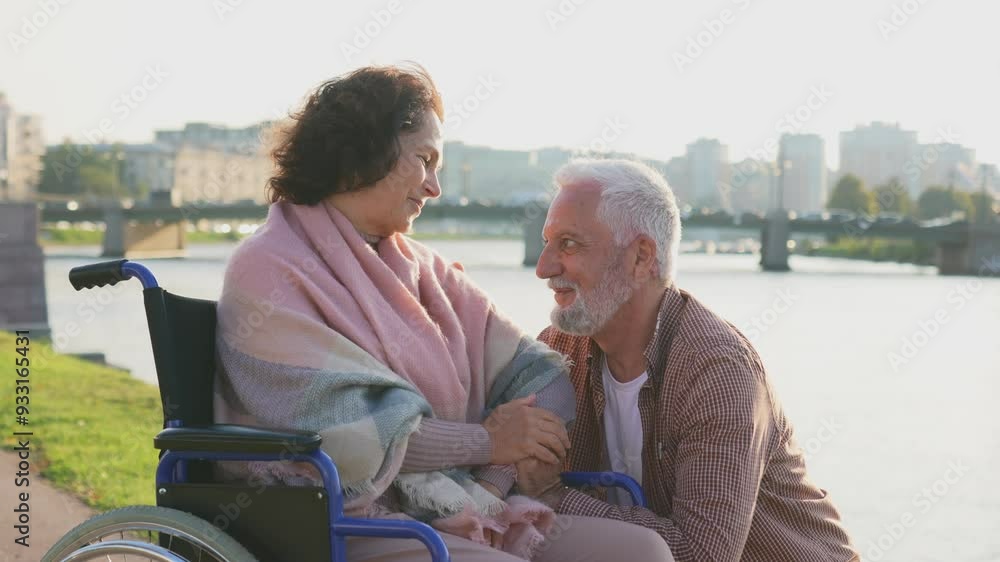 Senior woman in wheelchair walking with caregiver old man on road. Elderly family couple man supporting taking care of paralyzed woman in chair for people with disability outdoor. Rehabilitation Senior woman in wheelchair walking with caregiver old man on road. Elderly family couple man supporting taking care of paralyzed woman in chair for people with disability outdoor. Rehabilitation