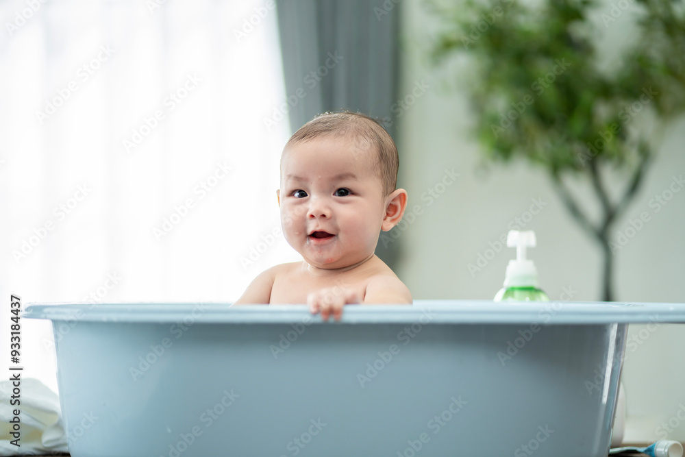 A baby is in a bathtub with a bottle of lotion next to it. The baby is smiling and looking at the camera A baby is in a bathtub with a bottle of lotion next to it. The baby is smiling and looking at the camera