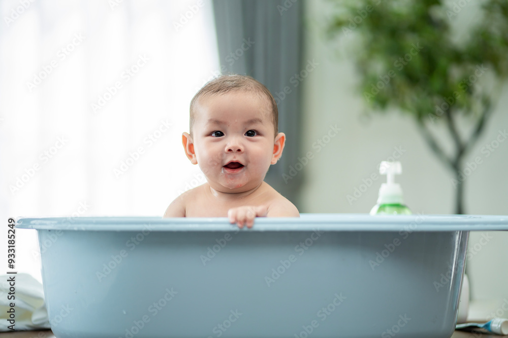 A baby is in a bathtub with a bottle of lotion next to it. The baby is smiling and looking at the camera A baby is in a bathtub with a bottle of lotion next to it. The baby is smiling and looking at the camera