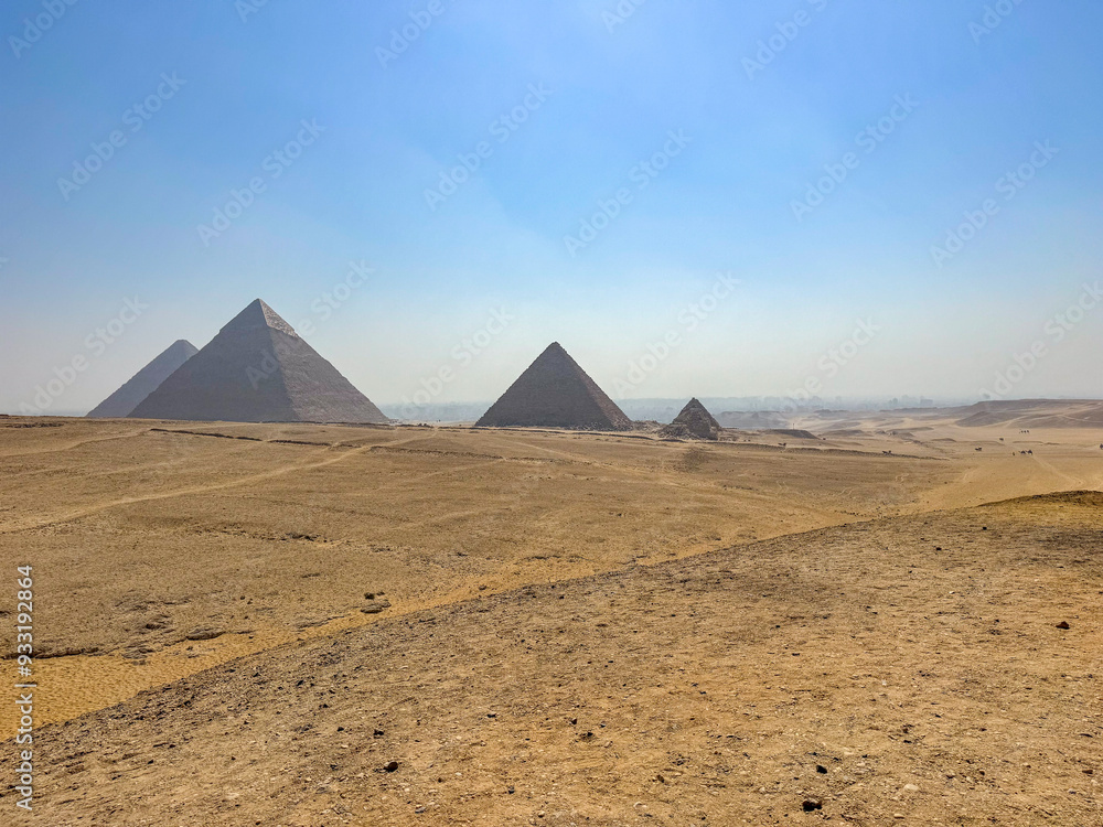 Pyramids of Giza with blue sky and desert in the foreground Pyramids of Giza with blue sky and desert in the foreground