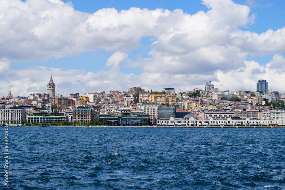 iconic Galata Tower rising above the historic buildings of Istanbul's waterfront. The vibrant cityscape is set against a backdrop of a bright blue sky with scattered clouds iconic Galata Tower rising above the historic buildings of Istanbul's waterfront. The vibrant cityscape is set against a backdrop of a bright blue sky with scattered clouds