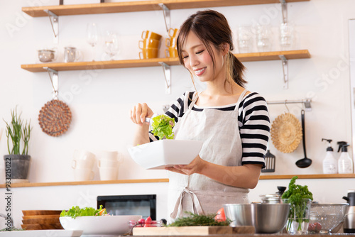 キッチンで料理を作る若い女性