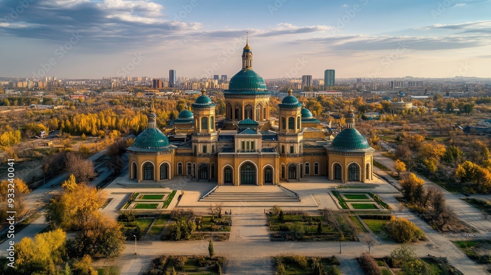 Fototapeta premium A majestic yellow building with teal domes and a symmetrical garden in front of it under a blue sky.