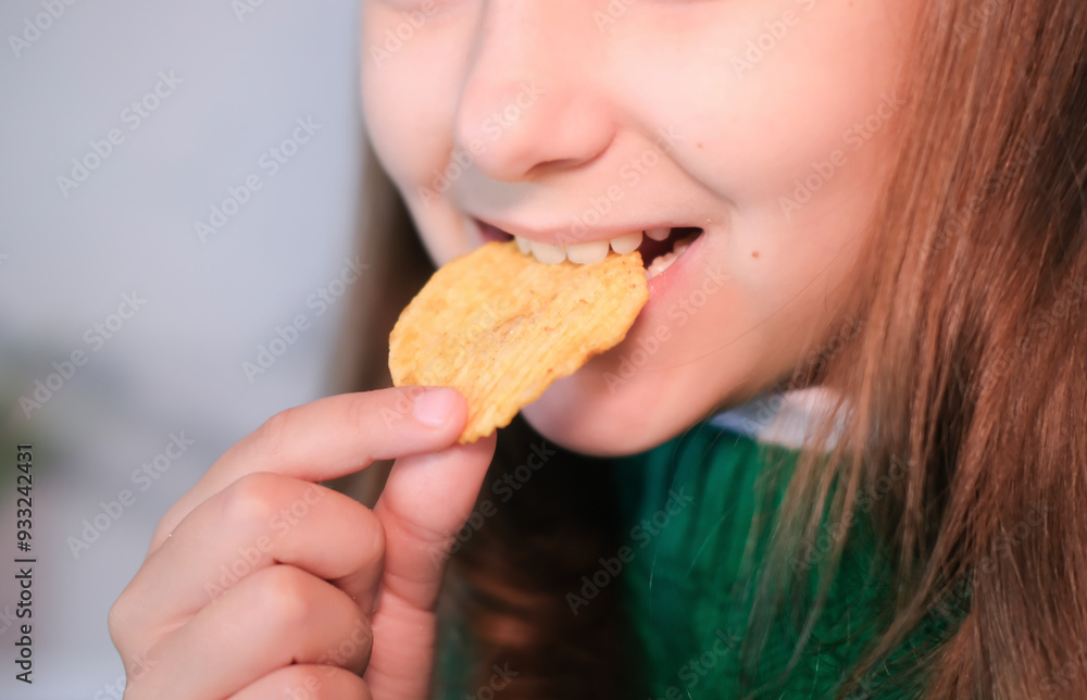 Child puts snack in his mouth with his hand and enjoys eating fast food, potato chips. Offer of tasty and unhealthy food for children. Childhood obesity concept. Child puts snack in his mouth with his hand and enjoys eating fast food, potato chips. Offer of tasty and unhealthy food for children. Childhood obesity concept.