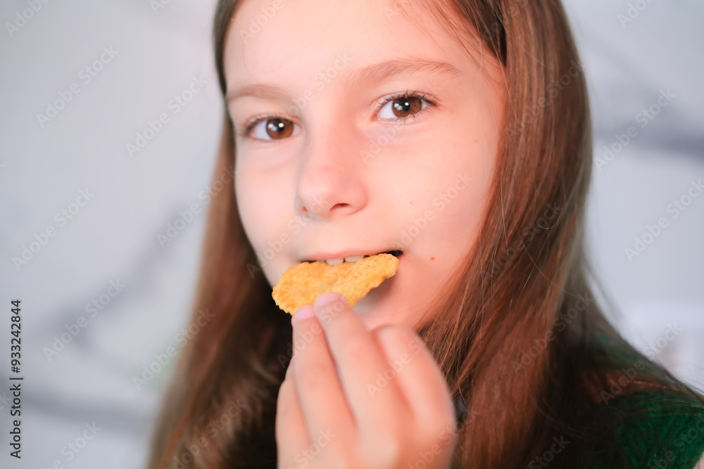 Child puts snack in his mouth with his hand and enjoys eating fast food, potato chips. Offer of tasty and unhealthy food for children. Childhood obesity concept. Child puts snack in his mouth with his hand and enjoys eating fast food, potato chips. Offer of tasty and unhealthy food for children. Childhood obesity concept.