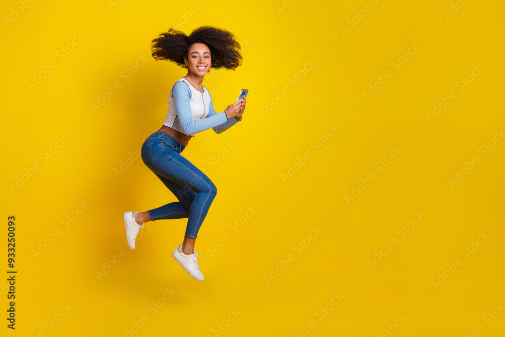 Full size photo of pretty young girl running hold telephone wear trendy blue outfit isolated on yellow color background Full size photo of pretty young girl running hold telephone wear trendy blue outfit isolated on yellow color background