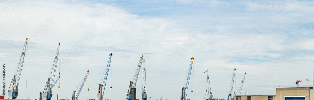 Industrial cranes in a row, transportation of goods in the port. Industry and trading port, transportation, lifting, Rotterdam, Netherlands. Industrial cranes in a row, transportation of goods in the port. Industry and trading port, transportation, lifting, Rotterdam, Netherlands.