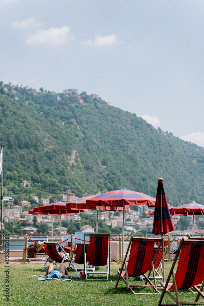 beach chairs and umbrellas on the lake shore in summer in Italy beach chairs and umbrellas on the lake shore in summer in Italy