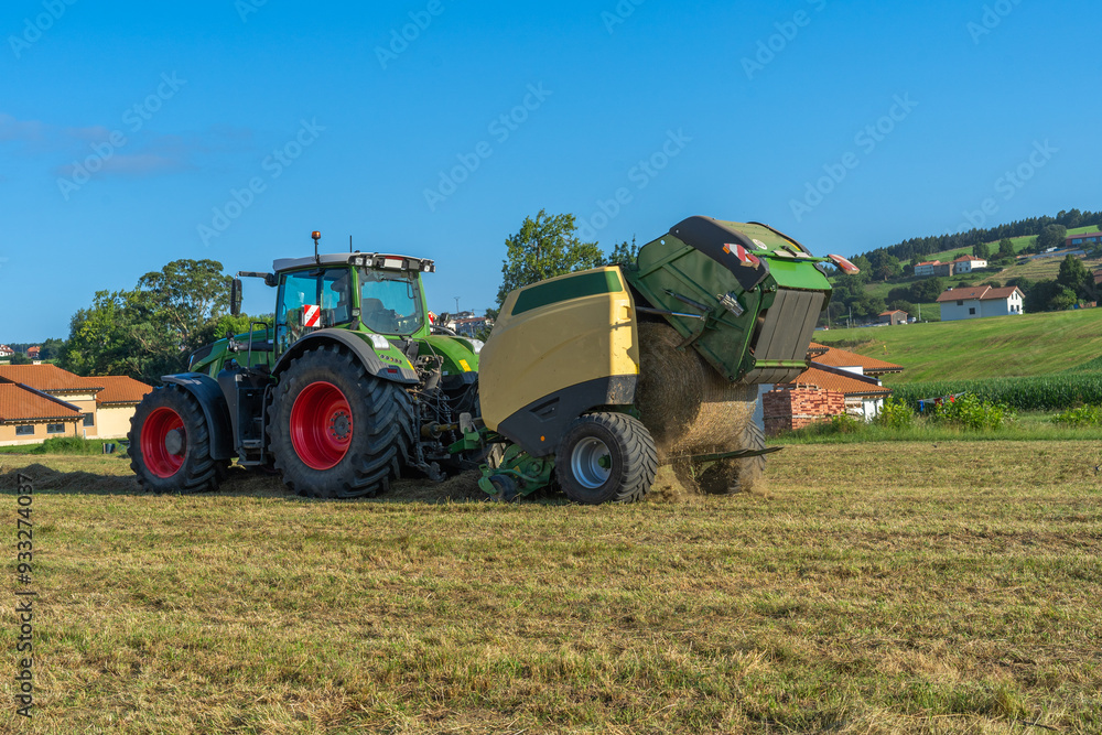 Obraz premium A farm tractor is pulling a grain harvester